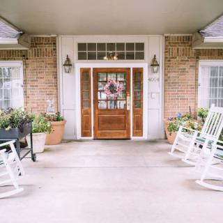 A welcoming front porch with rocking chairs and a decorated door.