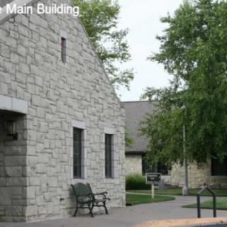 A stone building with benches and trees in an outdoor setting.
