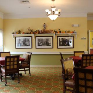 A cozy dining room with neatly arranged tables and chairs, featuring decorative wall art.