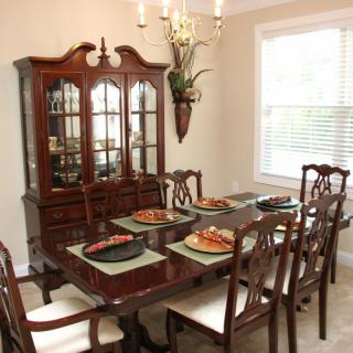A classic dining room setup with a wooden table, matching chairs, and a china cabinet against the wall.