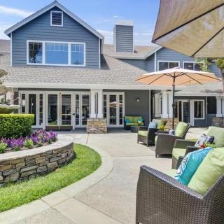 A welcoming patio area with comfortable seating and umbrellas in front of a modern house.