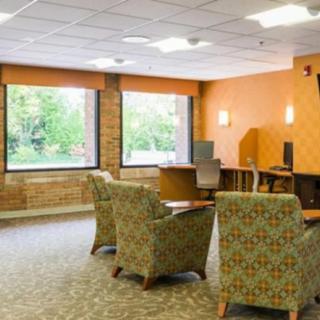 A comfortable lounge area with patterned chairs, tables, and large windows providing natural light.