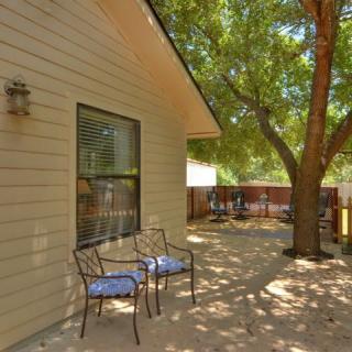 A peaceful backyard patio with chairs under the shade of a tree.