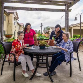A group of people sitting around a table outdoors, enjoying each other's company.