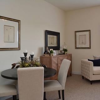 A cozy living room with a dining area, featuring elegant furniture and framed artwork on the walls.