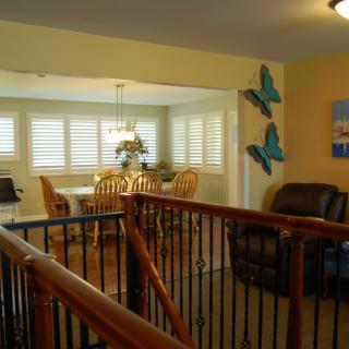 A cozy interior featuring a dining area with wooden chairs and a living space adorned with butterfly wall decor.