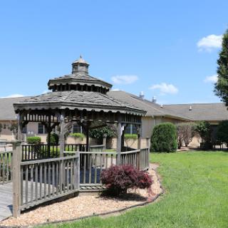 A beautifully designed gazebo set in a lush green garden under a clear blue sky.