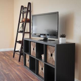 A modern living room setup with a TV on a storage cabinet and a ladder-style shelf.