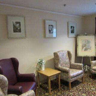 A cozy living room setup with armchairs, framed art on the wall, and a small table.