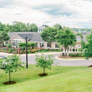 A peaceful residential neighborhood with houses and well-maintained lawns surrounded by trees.