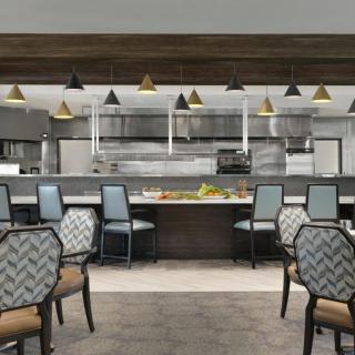 Modern restaurant interior featuring a dining area with patterned chairs and an open kitchen.