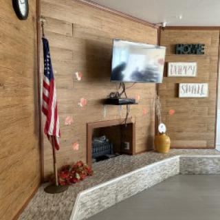 A cozy living room setup featuring a television, fireplace, and an American flag.