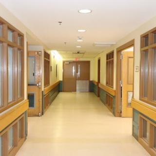 A quiet corridor within a hospital, featuring wooden accents and doors.