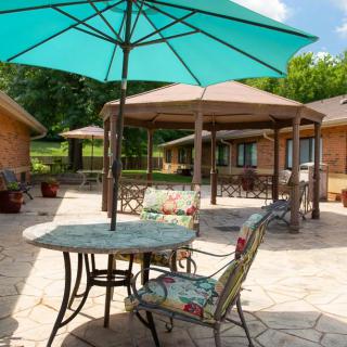 A sunny outdoor patio with tables, chairs, and umbrellas.