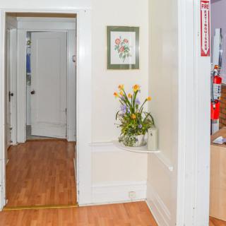 A hallway with wooden flooring, featuring a floral arrangement and artwork on the wall.