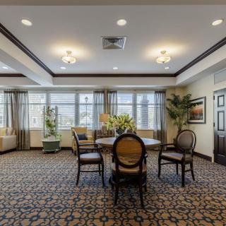 A spacious and elegant dining room with a central table, surrounded by chairs and large windows.