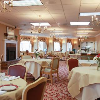 A spacious dining area with elegantly set tables, adorned with chandeliers and floral decor.