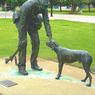 A bronze sculpture depicting a human interacting affectionately with a dog.