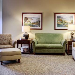 A well-furnished living room with sofas, armchairs, and decorative paintings.