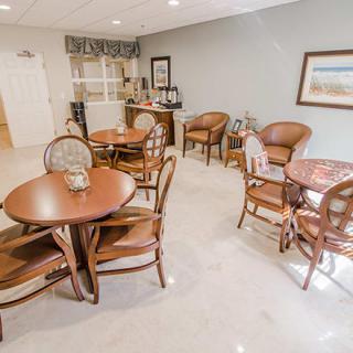 A cozy dining area with several tables and chairs, featuring simple decor and ample lighting.