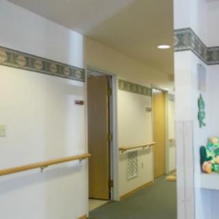 A hallway with multiple doors and a handrail along the wall.