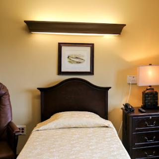 A cozy bedroom featuring a neatly made bed, soft lighting, and decorative artwork.