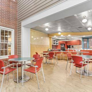 A modern cafe with red chairs and tables, featuring bright lighting and a casual ambiance.