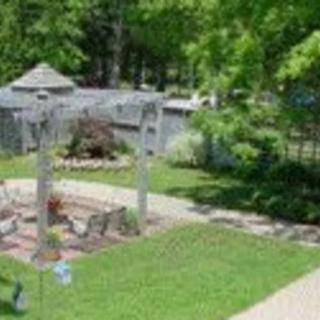 A peaceful garden setting with lush greenery, a gazebo, and a winding pathway.