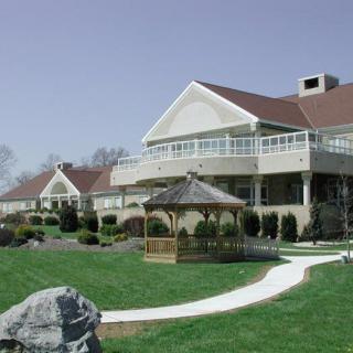 A scenic view of a large building with a gazebo and a winding pathway surrounded by grass.