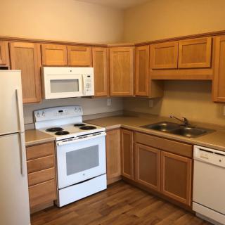 A kitchen with wooden cabinets, equipped with a refrigerator, stove, microwave, and dishwasher.