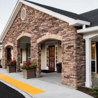 A brick facade building with a welcoming entrance and landscaped surroundings.