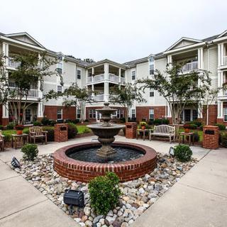 A beautifully landscaped courtyard with a central fountain surrounded by a residential building.