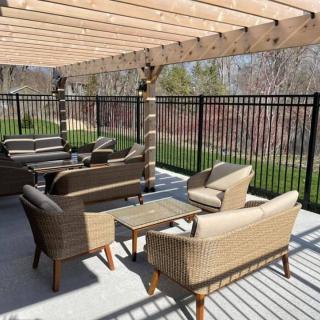 Outdoor patio with wicker furniture under a wooden pergola.
