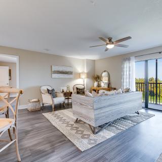 A modern living room with elegant furniture, ample natural light, and a stylish ceiling fan.