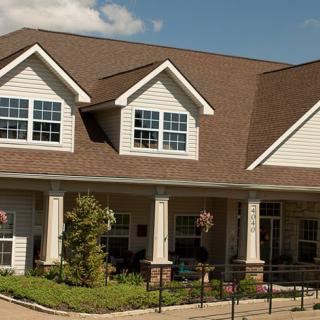 A large residential house with a front yard and a gabled roof under a clear sky.