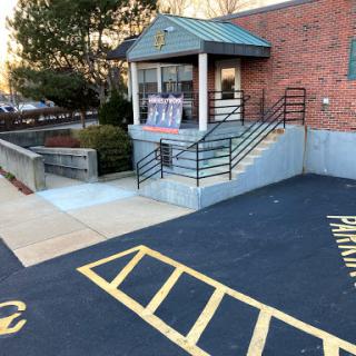 Entrance with steps leading up to a building, featuring a window booth and designated parking area.