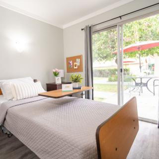 A minimalist bedroom featuring a hospital-style bed with a view of a patio through sliding glass doors.