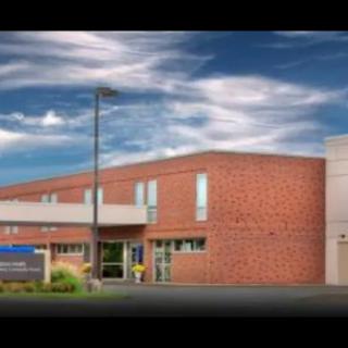 A modern brick hospital building under a cloudy sky.