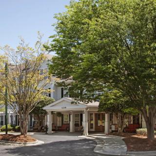 A front view of a building entrance surrounded by lush trees.
