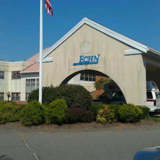 Exterior view of a building featuring signage and landscaping with an American flag.