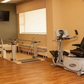 A physical therapy room equipped with exercise machines and parallel bars.