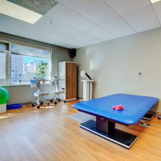 A well-equipped physical therapy room featuring a blue treatment table and various exercise tools, designed for rehabilitation purposes.