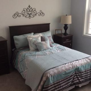 A neatly arranged bedroom with a bed, decorative pillows, and a lamp on the nightstand.