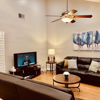 A cozy living room with modern decor, featuring leather sofas, a TV, and stylish artwork.