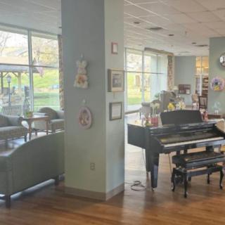 A cozy lounge area featuring a piano and comfortable seating with large windows.