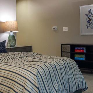 A cozy bedroom with striped bedding, a bedside lamp, and modern artwork on the wall.