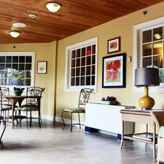 A cozy interior space featuring tables, chairs, and decorative artwork, with warm lighting.