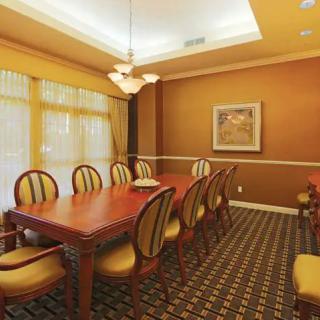 A cozy dining room with a wooden table, surrounded by upholstered chairs, featuring warm lighting and decorative artwork.