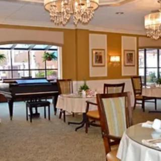 An elegant dining room with chandeliers and a grand piano.