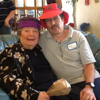 A joyful moment shared between two seniors wearing colorful hats.